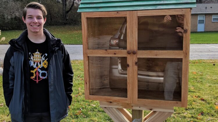 Jeremiah Lewis stands next to the little free library he built in Vinton Woods neighborhood.