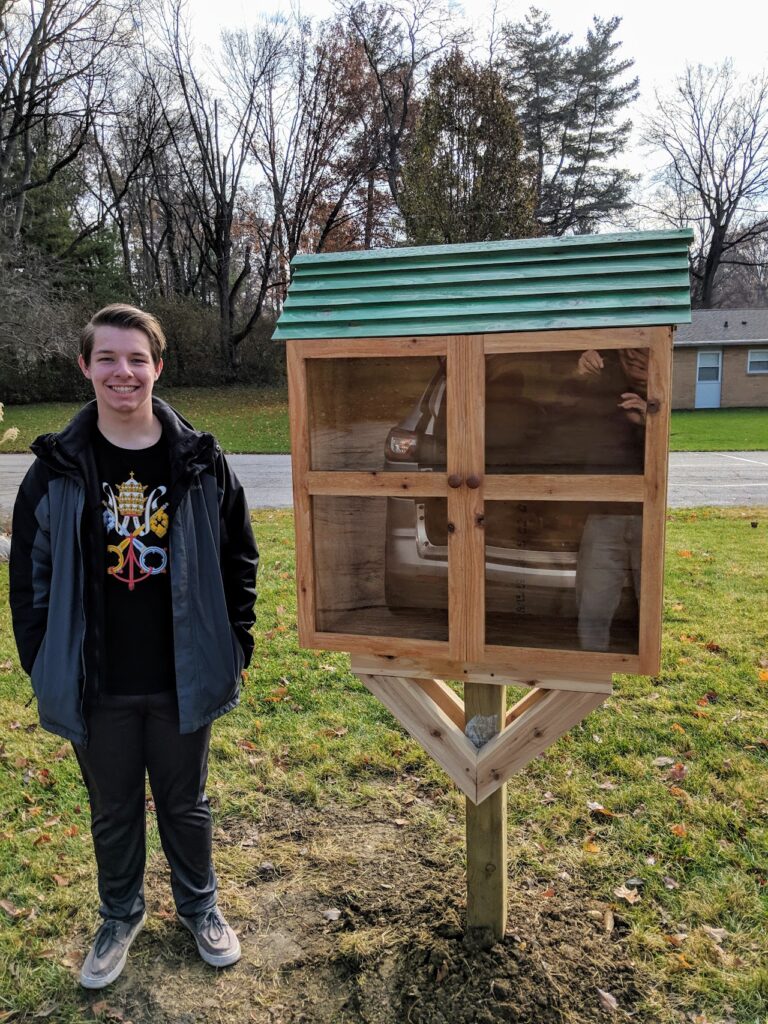 Jeremiah Lewis stands next to the little free library he built in Vinton Woods neighborhood.